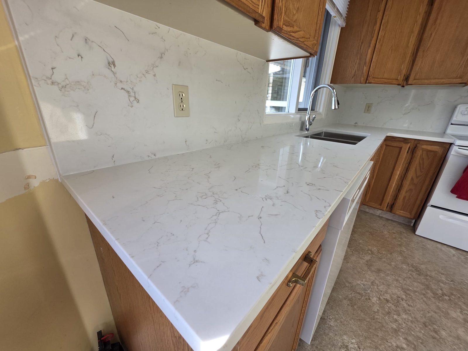 Marble-look quartz countertop with full-height backsplash in a Kelowna kitchen